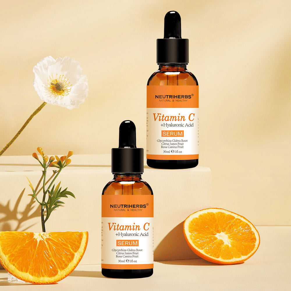 Neutriherbs Vitamin C + Hyaluronic Acid Serum 30 ml tillsammans med färska apelsiner och blommor. Inspirerande produktbild som lyfter fram serumets innehåll av C-vitamin för återfuktad hud, ökad lyster och en jämnare hudton.